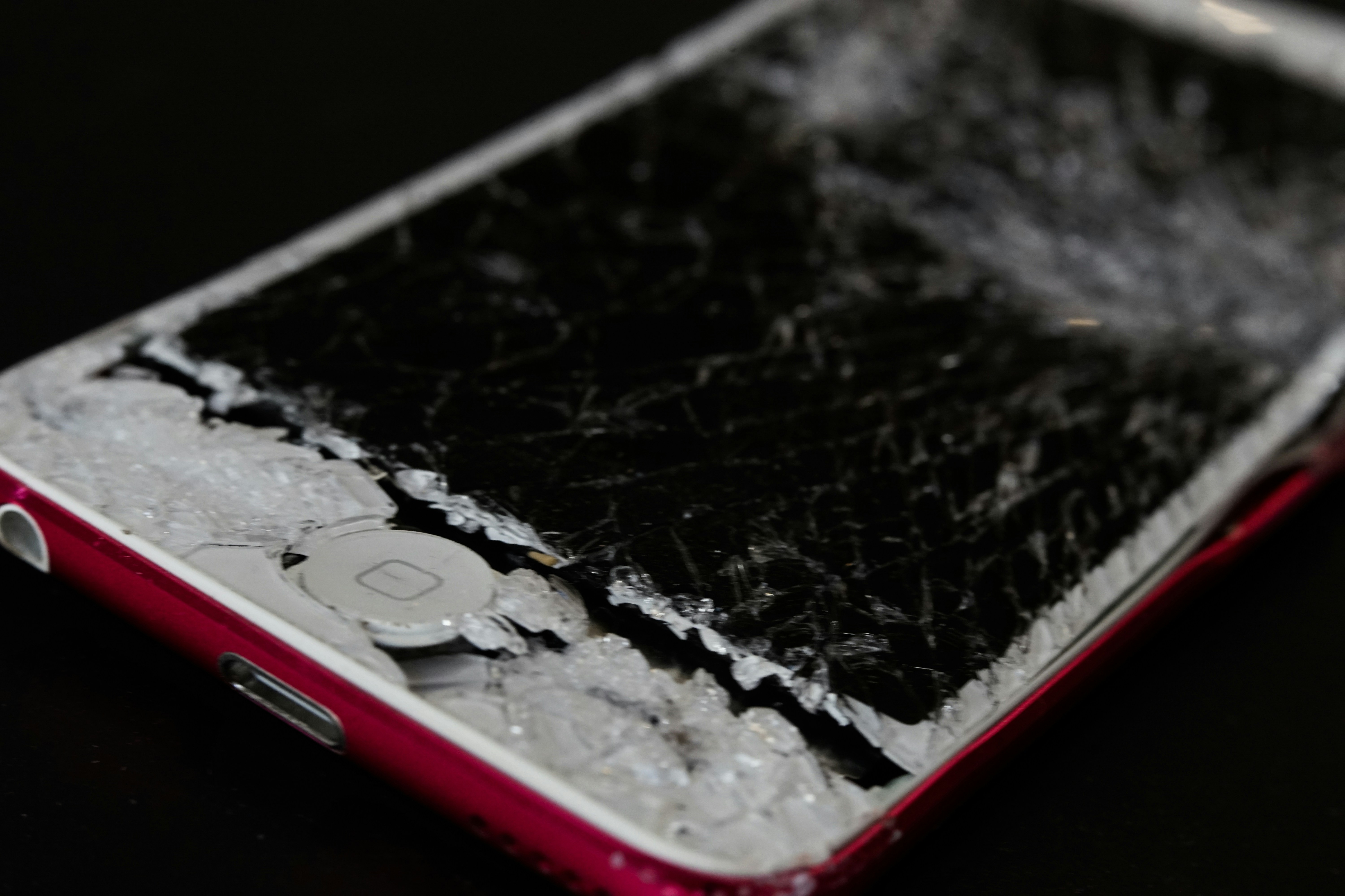 An iPhone that's experienced to many impacts. It's screen is aa shattered spiderweb of glass.